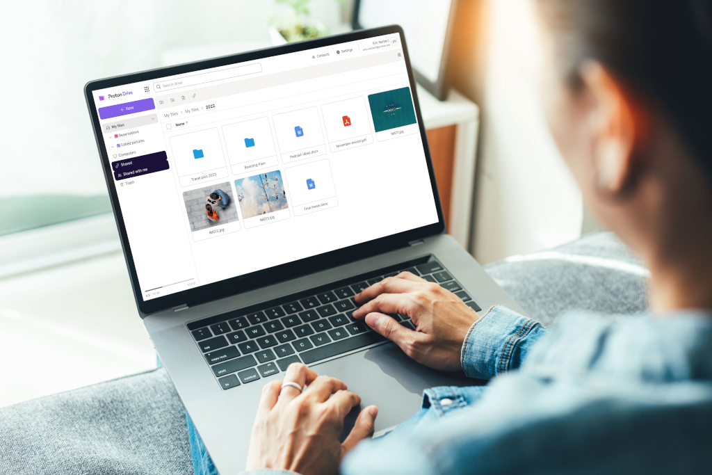 Persona utilizando un ordenador portátil mientras navega por Proton Drive, una plataforma de almacenamiento en la nube con carpetas y archivos visibles en la pantalla.