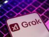 Teléfono móvil con el logo de Grok, el chatbot de inteligencia artificial de xAI, sobre un teclado iluminado con luces en tonos morados y rosados.