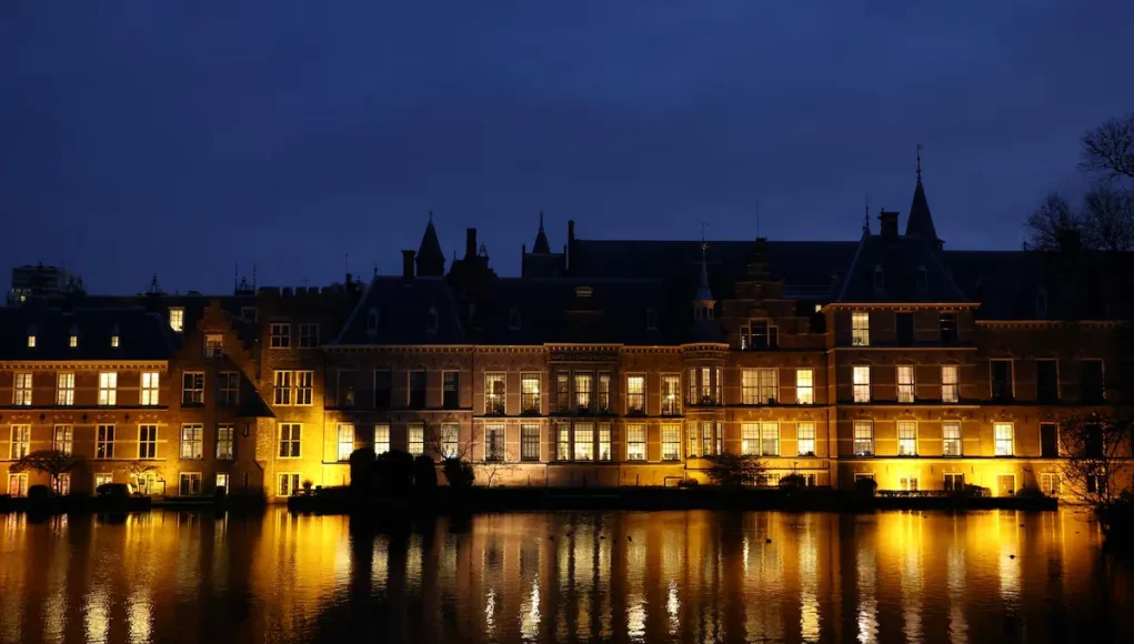 Edificio del Binnenhof en La Haya, Países Bajos, iluminado por la noche, con su reflejo en el agua.