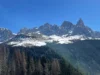 Los árboles de abeto se comunican durante un eclipse solar Paisaje montañoso de los Dolomitas con picos nevados al fondo, bosques de coníferas en primer plano y cielo despejado.