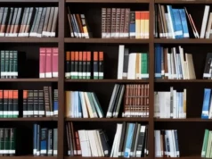Bélgica bloquea la Open Library de Internet Archive en una orden judicial sin precedentes Estantería de madera oscura repleta de libros de distintos tamaños y colores, algunos colocados en posición vertical y otros inclinados. La imagen transmite un ambiente de biblioteca o estudio.