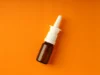 FDA aprueba primer spray nasal diurético para enfermedades del corazón, hígado y riñón Frasco marrón pequeño con aplicador en spray nasal blanco, colocado sobre un fondo naranja.