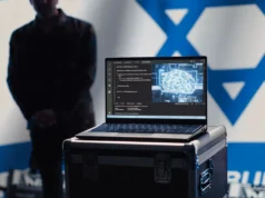 Israel contrata empresa estadounidense para entrenar ChatGPT con narrativas pro-israelíes Portátil abierto sobre una caja metálica mostrando en la pantalla un editor de código con líneas en C y, al lado, una ilustración digital de un cerebro con conexiones neuronales luminosas, representando inteligencia artificial. Al fondo se distingue de manera borrosa una persona y parte de la bandera de Israel en la pared.