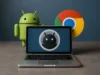 Google revela Aluminium OS: el sistema operativo que fusionará Android y ChromeOS con IA en su núcleo Un portátil abierto sobre una superficie lisa muestra en su pantalla un icono estilizado del robot de Android en tonos oscuros. Detrás del portátil se ven dos figuras: una figura tridimensional del robot verde de Android a la izquierda y un gran logotipo circular de Google Chrome a la derecha, ambos sobre un fondo azul grisáceo.