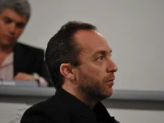 Jimmy Wales provoca una tormenta en Wikipedia al intervenir en el polémico artículo sobre «genocidio de Gaza» Hombre de mediana edad, con barba corta y cabello corto peinado hacia atrás, observado de perfil mientras asiste a un evento o conferencia. Viste ropa oscura y aparece concentrado mirando hacia el frente. En el fondo, otra persona está sentada, ligeramente desenfocada.